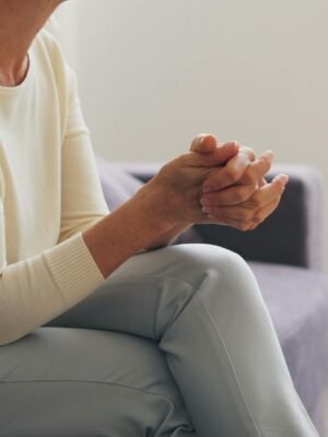 An elderly woman seated thoughtfully in an indoor counseling setting.